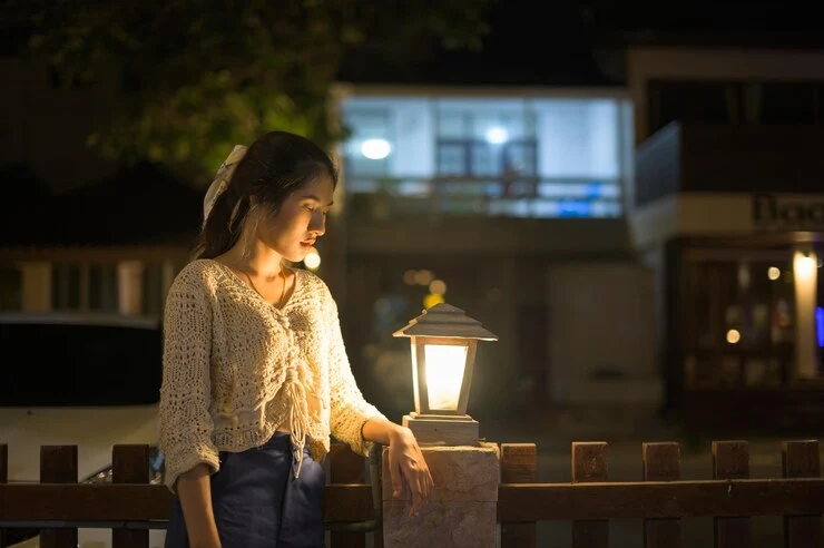 kvinne som ser på en opplyst lampe om natten