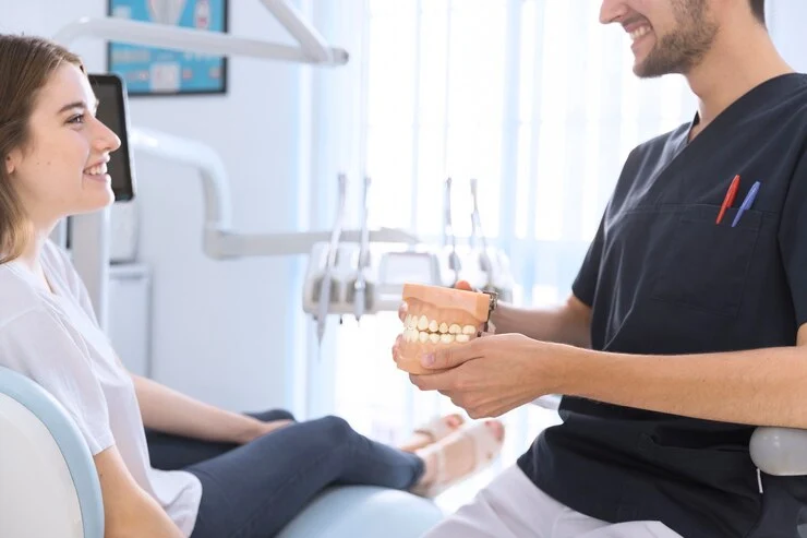 mannlig tannlege viser tannmodell til pasient